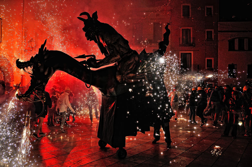 El Cabrot en plena cercavila de foc, amb espurnes i foc vermell omplint la plaça del Vendrell